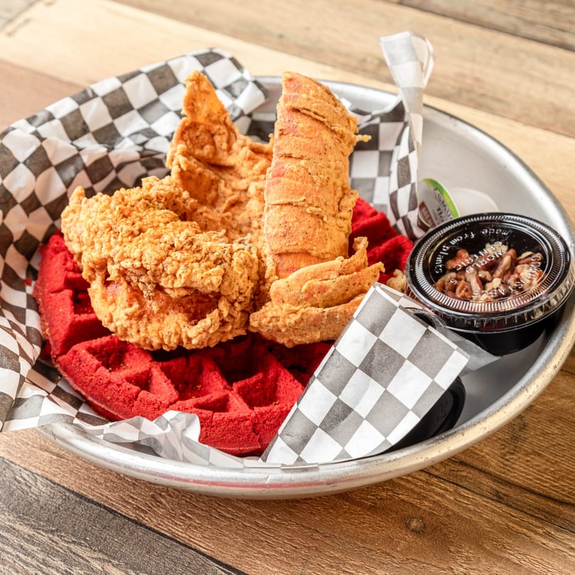 Krustaceans Seafood's fried lobster and chicken tenders on a red velvet waffle with syrup.